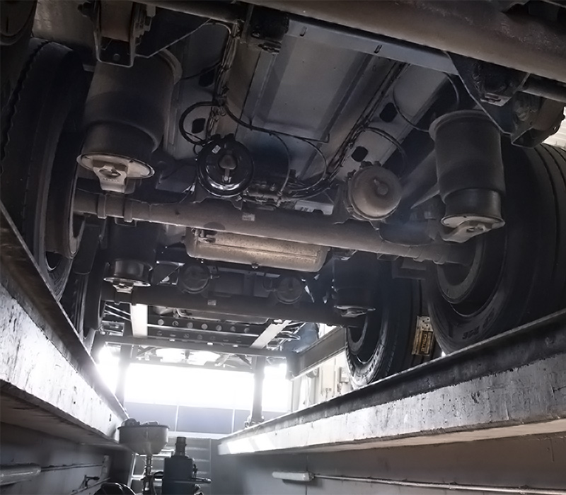 Fotografie aus der Grube einer Lkw-Werkstatt mit Sicht auf die Achsen eines Lkw-Aufliegers - BTS Aufliegerservice