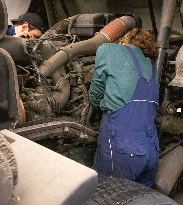 Mechanikerin und Mechaniker arbeiten an einem Lkw-Motor in der Dortmunder Lkw-Werkstatt von BTS